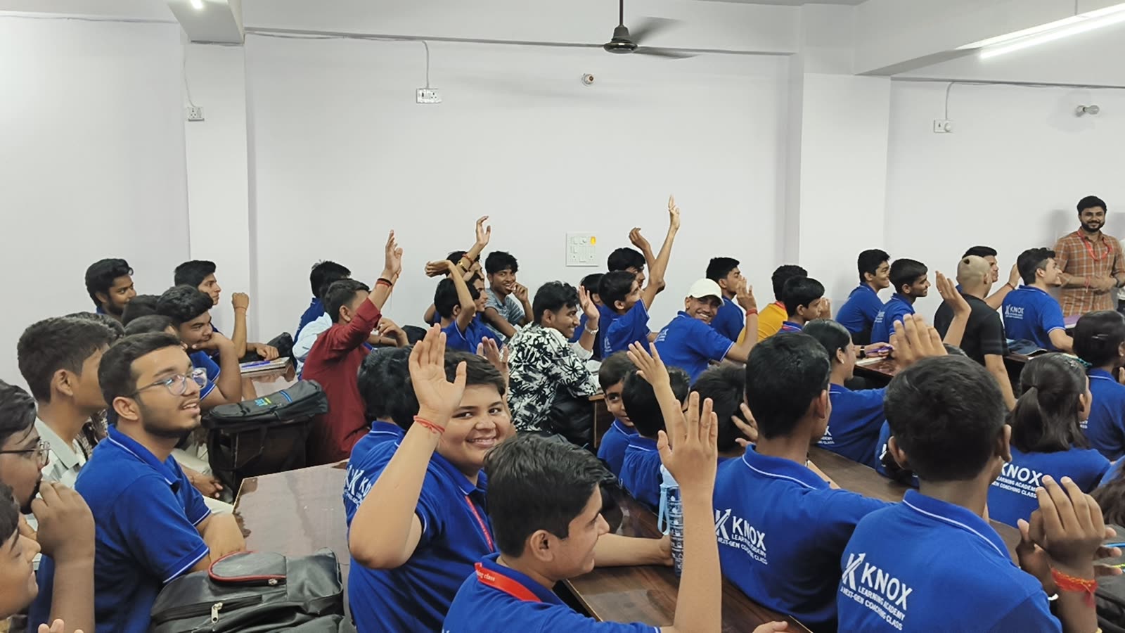 Students with their hands raised in a Knox Learning Academy classroom